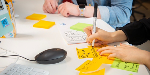 Hands drawing on sticky notes