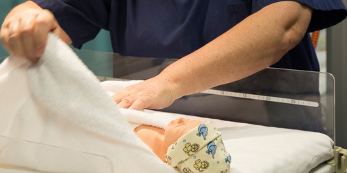 a nurses' hands are putting a blanket around a baby dummy