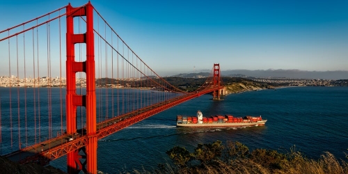 Golden Gate Bridge with a cargo ship passing below it