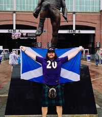 man standing in front of stature holding saltire flag
