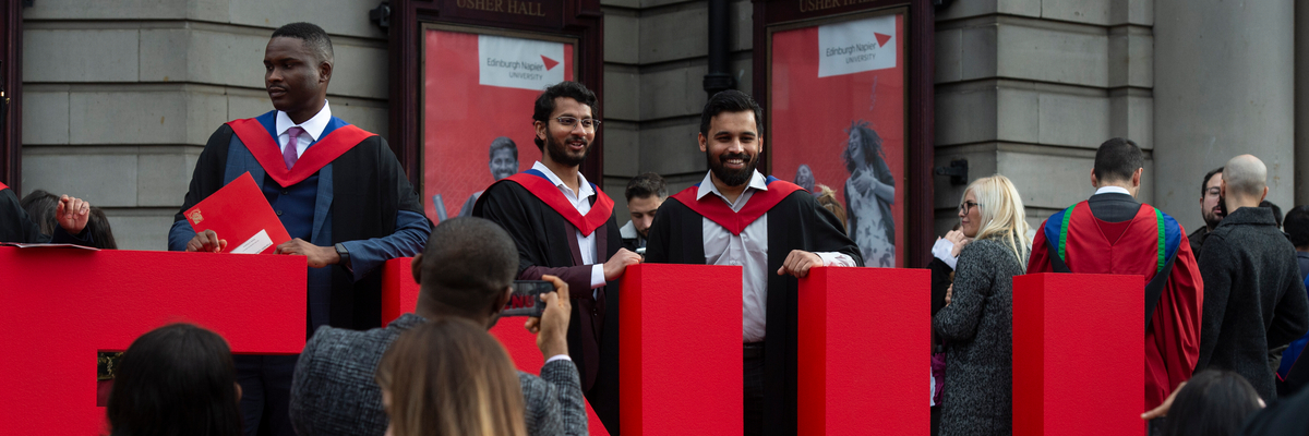 Graduation students taking pictures with an ENU sign outside Usher Hall.
