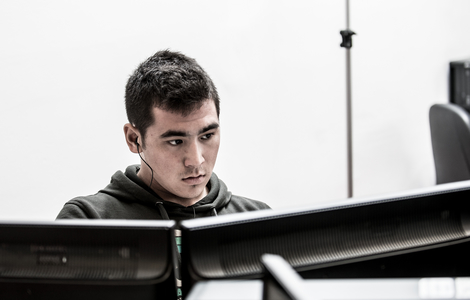 Student concentrating in front of dual computer monitors