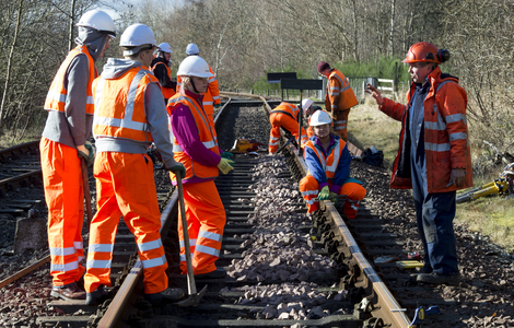 Undergraduates wearing high visibility safety clothing while repairing a railway line