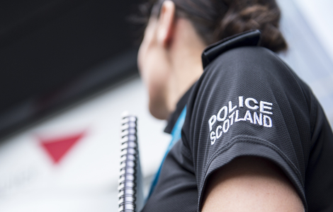 Police officer's sleeve with police Scotland logo as the female officer looks to Edinburgh Napier University's Sighthill Campus