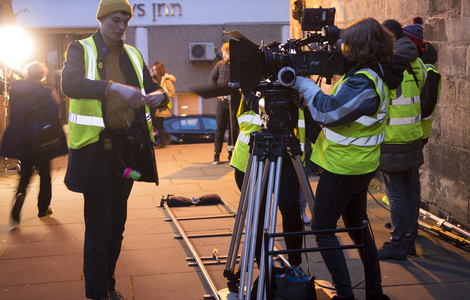 Film students wearing high visibility jackets with camera equipment working on location around the High Street in Edinburgh