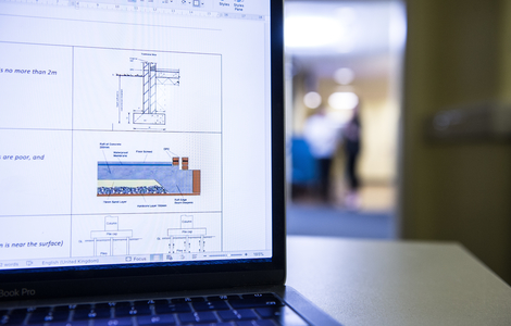 A laptop with blue prints on it and people in the background