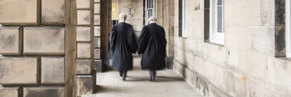 Two advocates walking away from the camera outside the courts at Parliament Square.