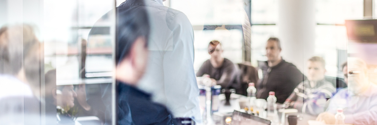 Businessman giving a presentation with the reflections of people in the glass