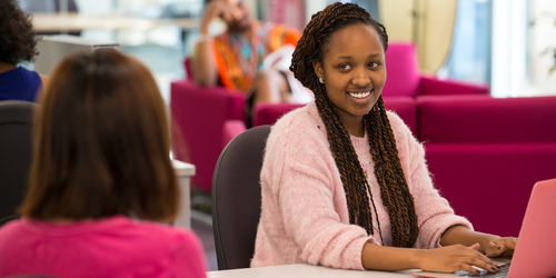Photo of Edinburgh Napier University students smiling and chatting in the library