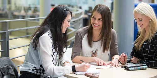 Law students at Edinburgh Napier University sitting around a table chatting and laughing