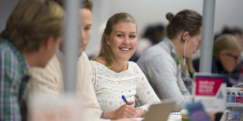 Photo of Edinburgh Napier University students chatting whilst working in the library