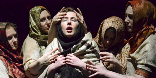 Students performing in 'Trojan Barbie' with 4 people with shawls over their head huddled round one person in the middle with an open mouth
