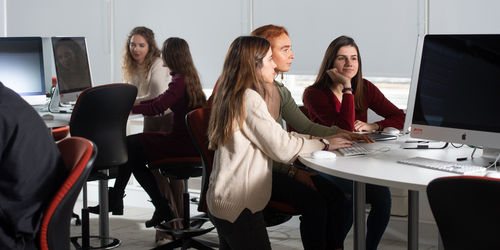 A class of female students working on Apple computers