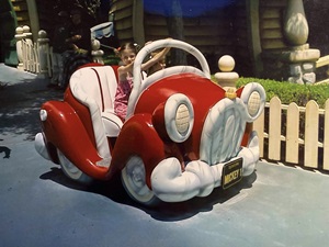 Iona as a young child sitting in a toy car 