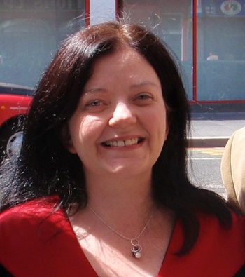 A close-up image of Joanne Sharp - a woman smiling at the camera with dark hair and wearing a red top