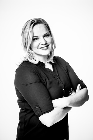 A black and white photo of Mia Yl&ouml;nen. Smiling at the camera with arms folded