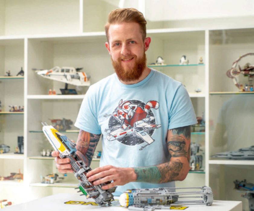 Jordan Scott holding a lego sculpture with pre-built models in the background