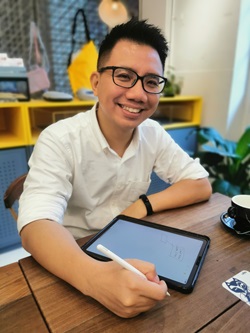 Lawrenz Tan sitting at a table writing on a tablet