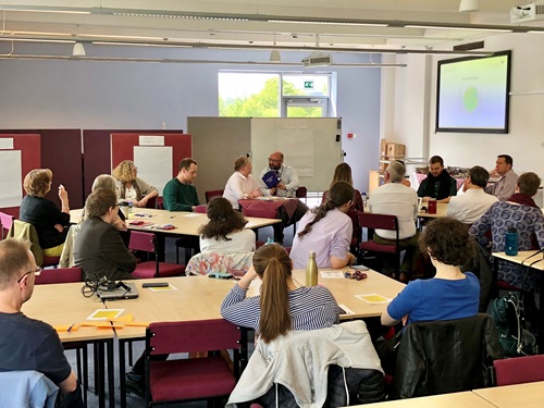A group of staff attending a strategy engagement session, sitting around desks and having a discussion