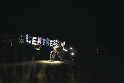 A cyclist in front of the illuminated Glentress sign at Light Up The Trails