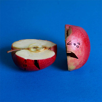 Apple split in half with a crying face drawn on
