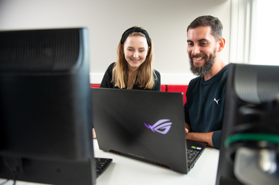 Two school of computing students working together on an open laptop. 