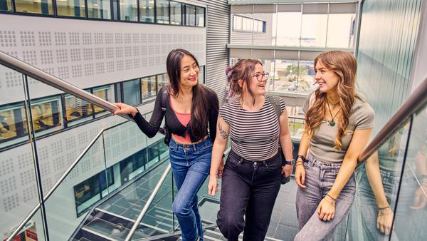 3 students on the stairs at Sighthill chatting and smiling