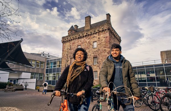 A photograph of two students leaving Merchiston campus on their bikes at the end of the day. 