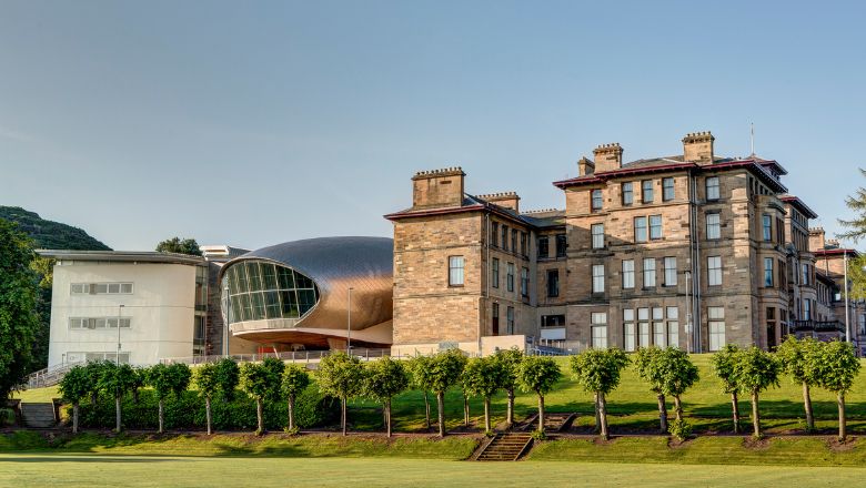 The traditional stone building and modern extension of Craiglockhart campus on a sunny day. 